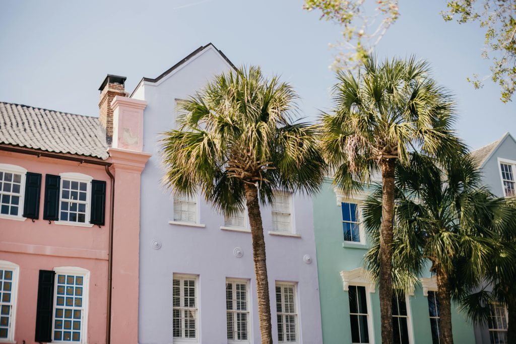 Vibrant pastel homes and palm trees on a sunny street in Charleston.